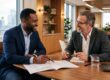 A business owner and a seasoned financial advisor leaning in together over a strategy document in a modern office